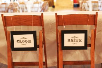 Chairs with Bride and Groom signs on them.