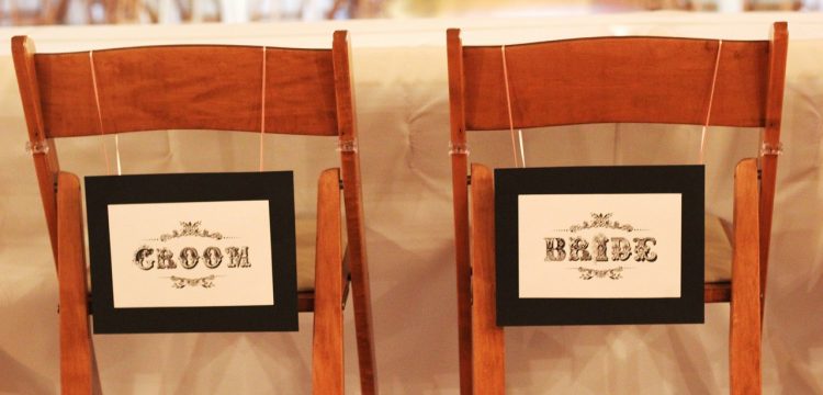 Chairs with Bride and Groom signs on them.