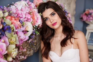 Model leaning against a row of wedding flowers.