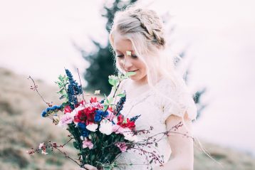 Bride in a field with wedding flowers.