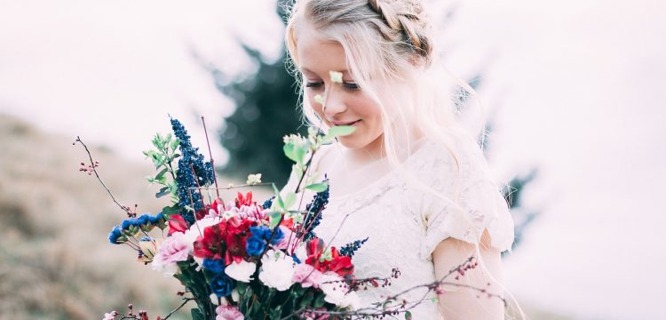 Bride in a field with wedding flowers.