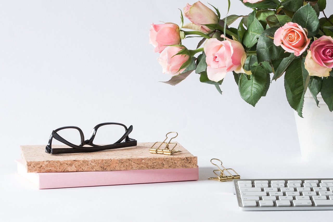 Part of a keyboard, glasses, and pink roses.