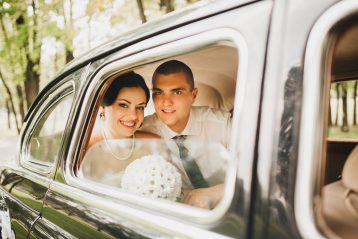 Bride and groom in the back seat of a car.