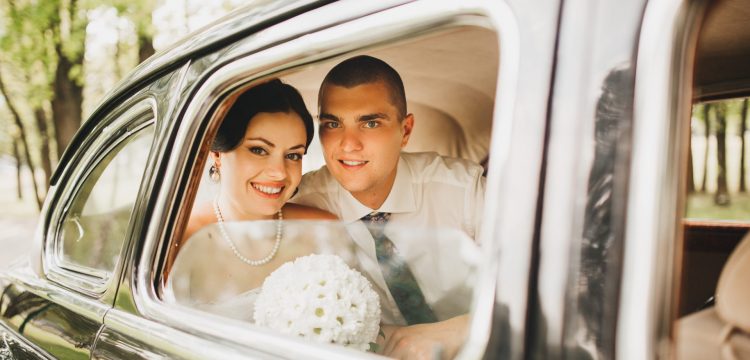 Bride and groom in the back seat of a car.