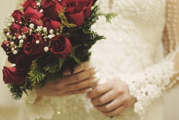 Bride holding a bouquet of red roses.