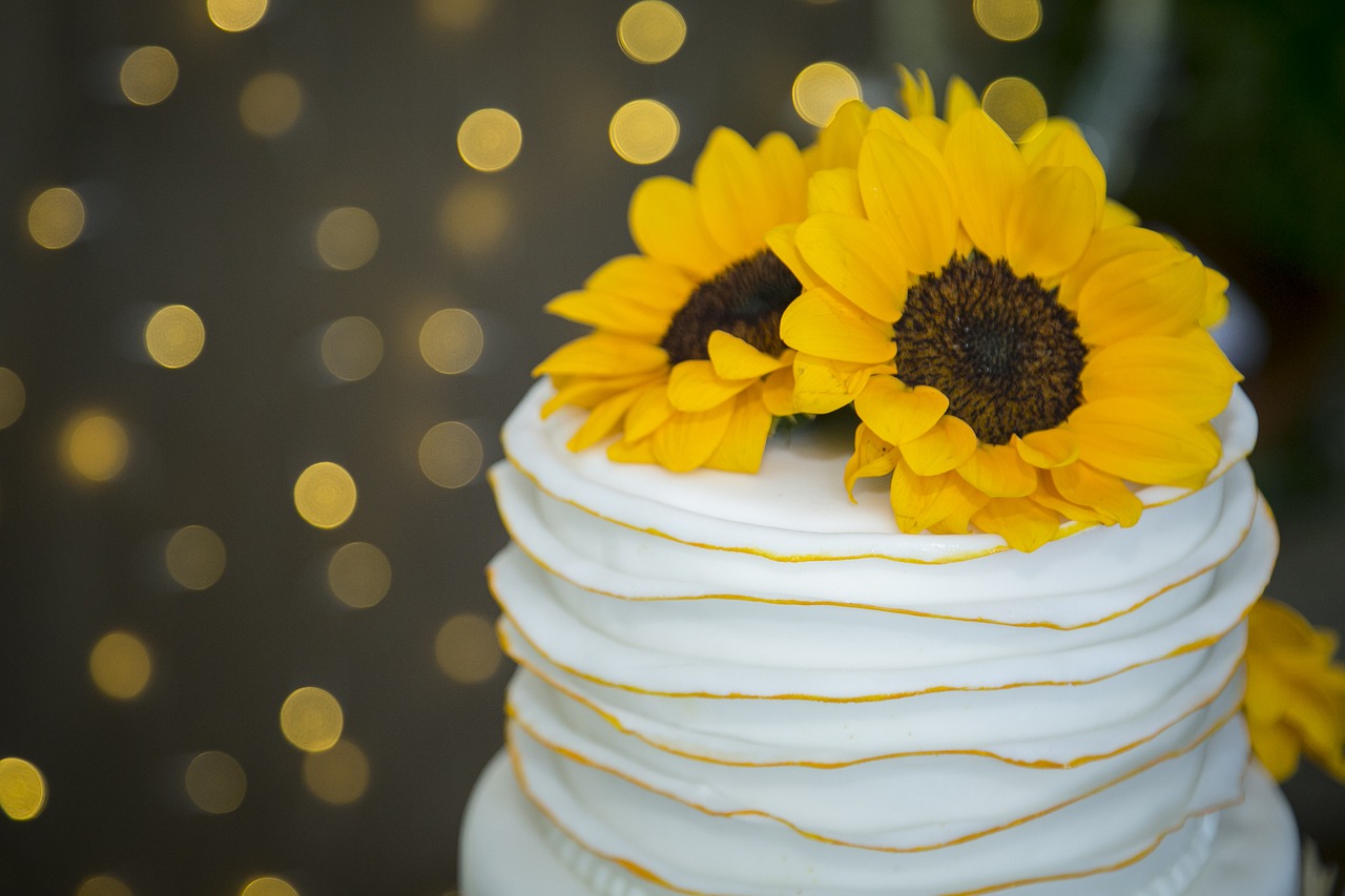 A single tiered wedding cake with a sunflower on top.