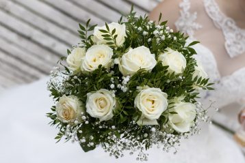 White roses with greenery in a wedding bouquet.