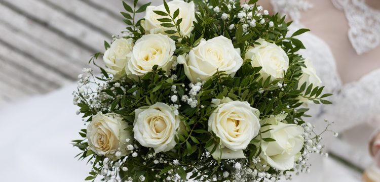 White roses with greenery in a wedding bouquet.
