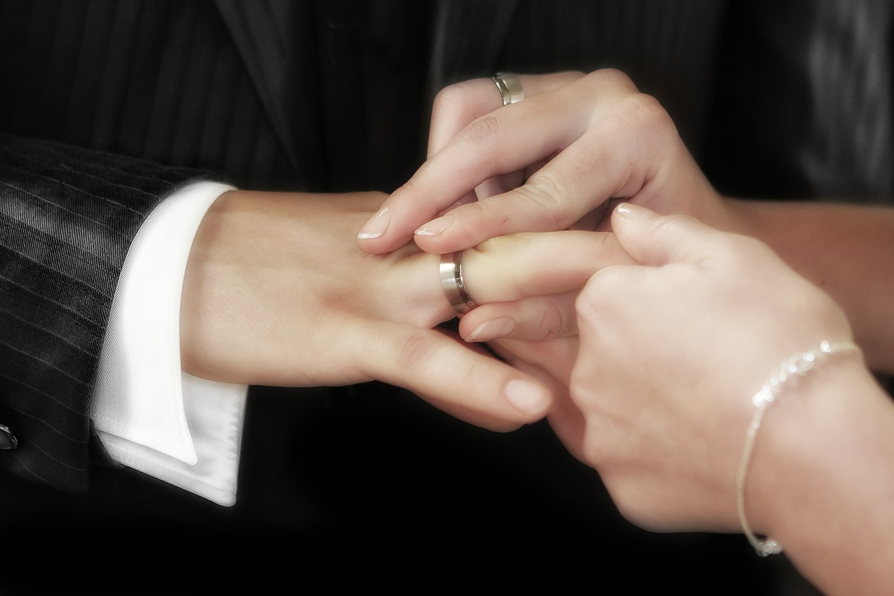 Bride placing a wedding band on the groom.