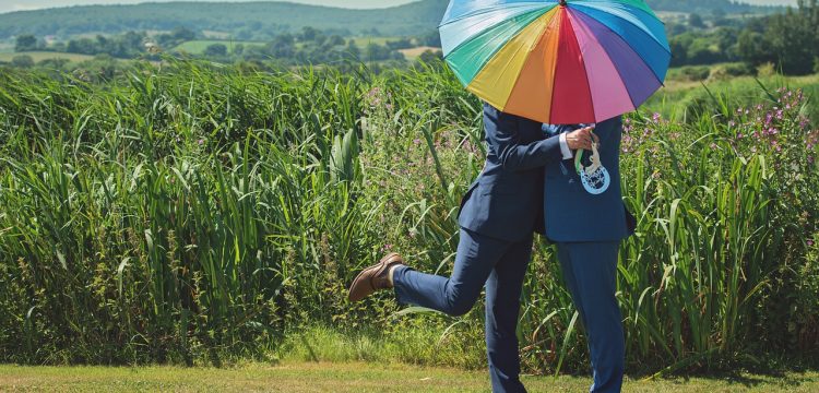 Two grooms with a rainbow umbrella.