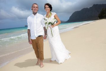 Bride and groom walking a Hawaiian beach.