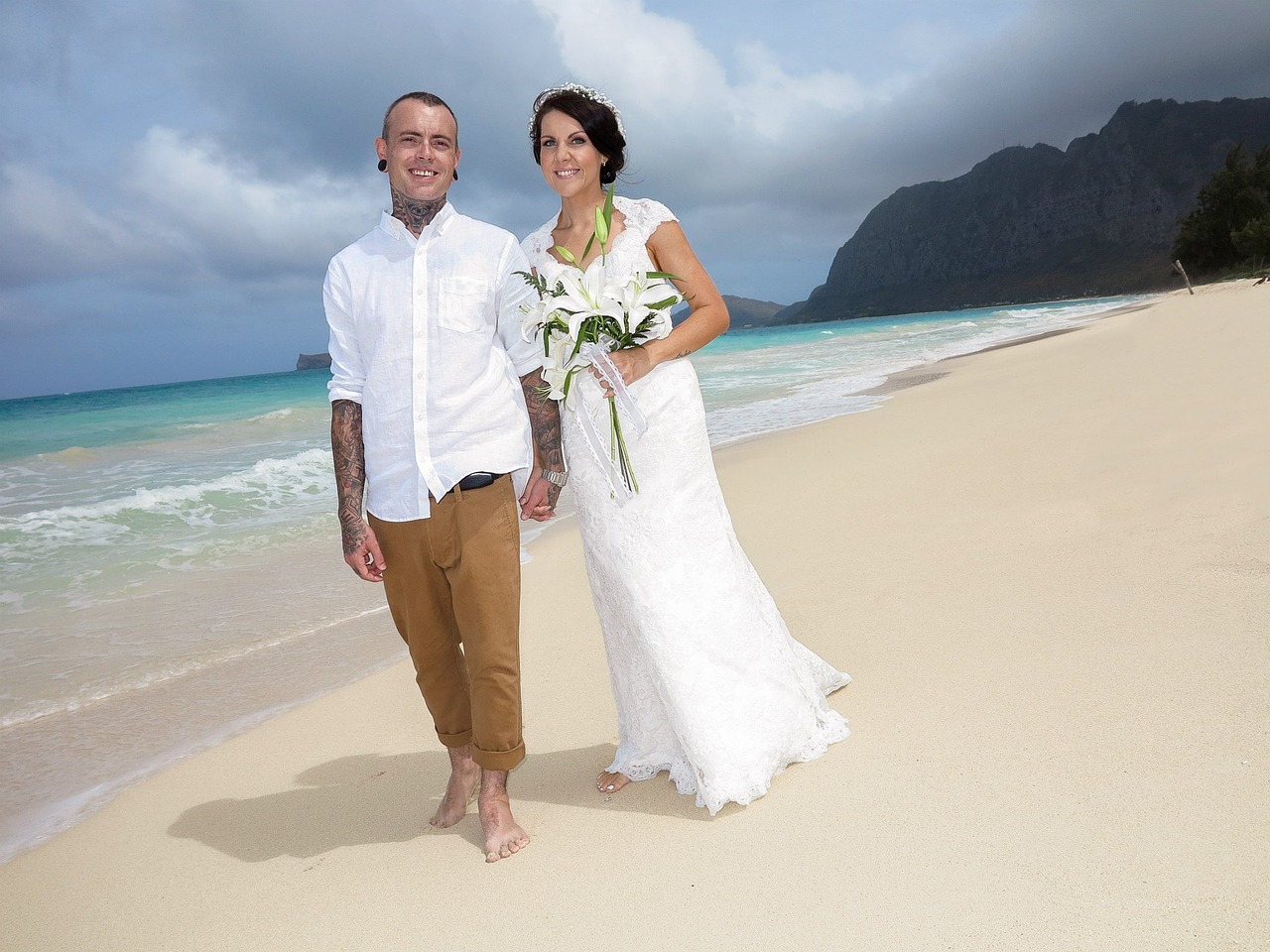 Bride and groom walking a Hawaiian beach.