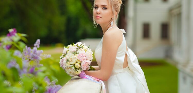 Bride with her bouquet, leaning on a railing.