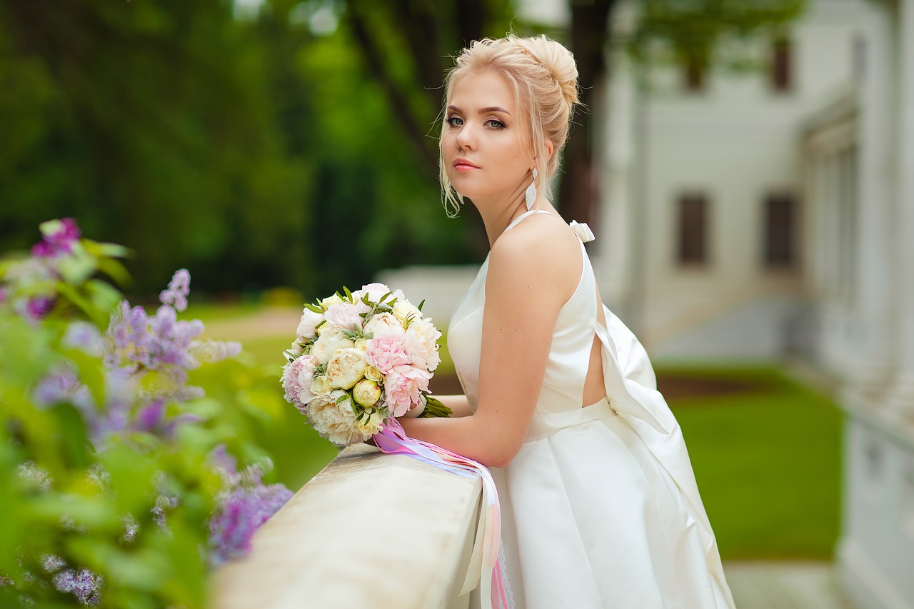 Bride with her bouquet, leaning on a railing.