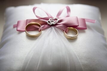 Wedding pillow with two rings tied to it.