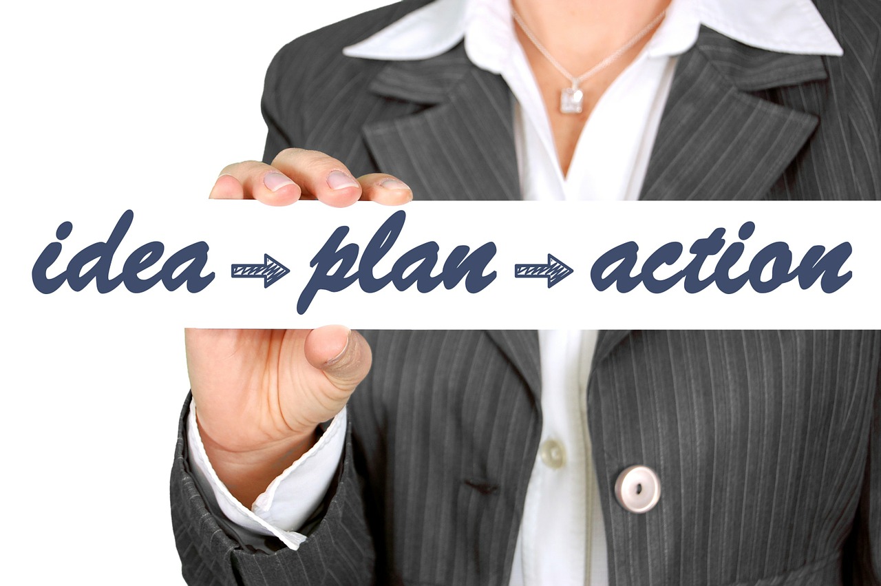 Businesswoman holding sign that reads, "idea - plan - action".