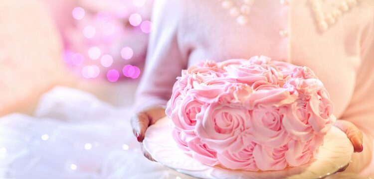 Woman in pink sweater holding a pink cake.