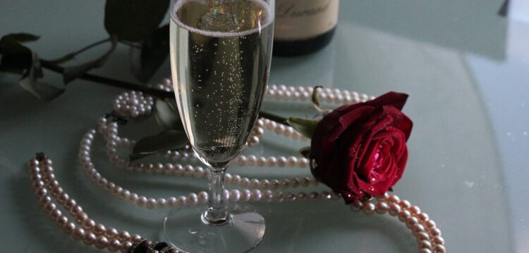 Champagne with pearls and a red rose.