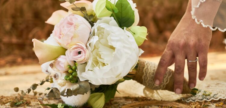 Bride's hand touching a wedding bouquet.