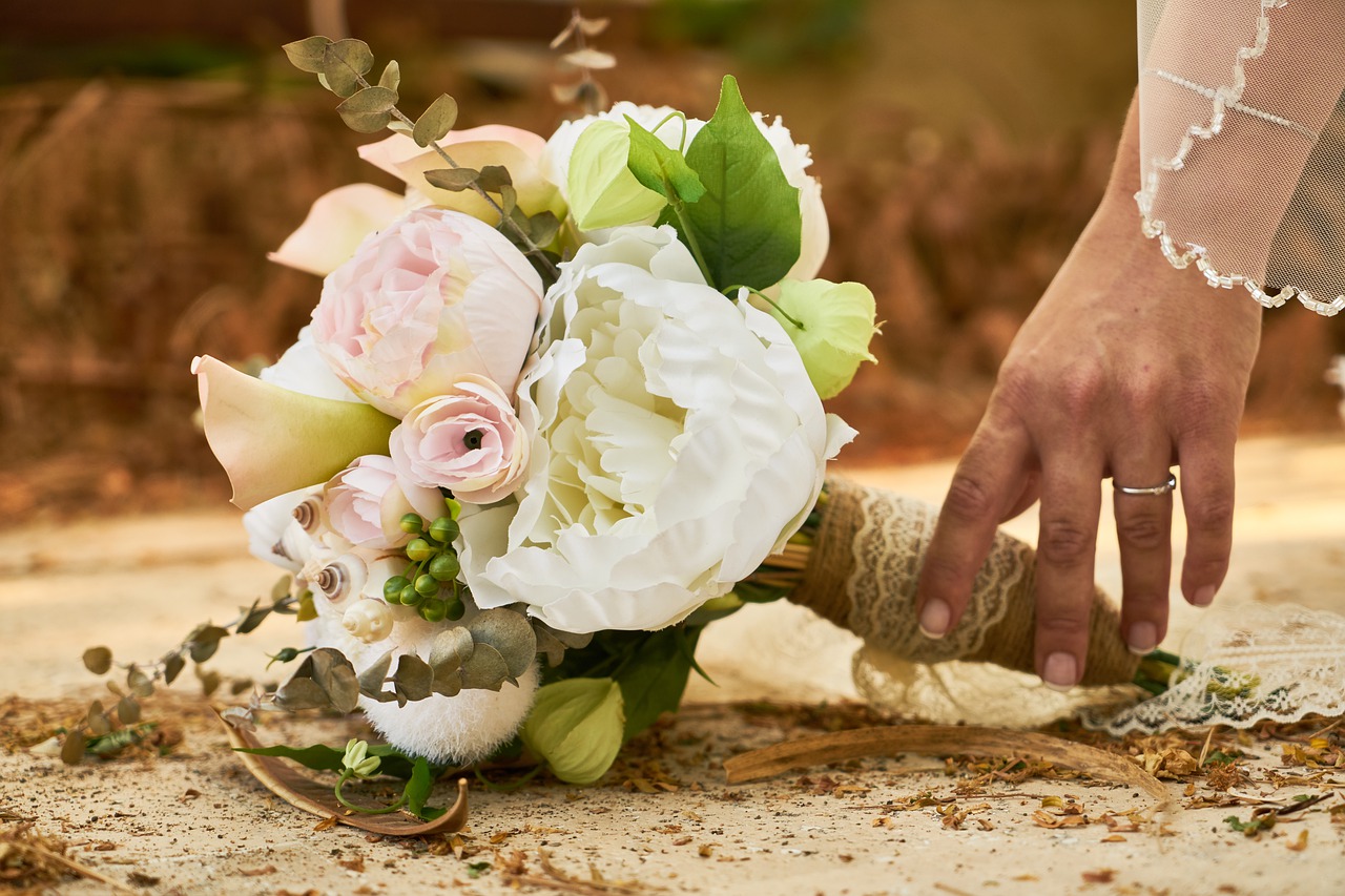 Bride's hand touching a wedding bouquet.