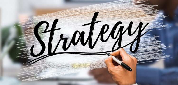 Person writing the word "Strategy".